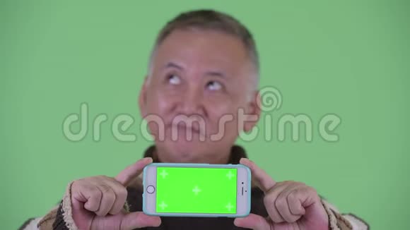 一脸快乐成熟的日本男人一边看手机一边思考视频的预览图