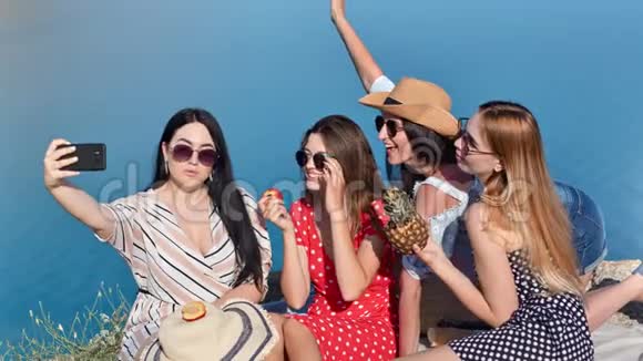 一群快乐的年轻女性朋友在海景背景下使用智能手机自拍视频的预览图