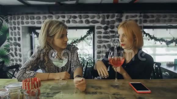 两个女人坐在酒吧柜台旁喝着鸡尾酒有趣地交谈着视频的预览图