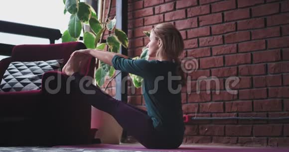 在一个现代的房子里在一个放松的空间里女士早上练习瑜伽她伸展腿和身体感觉很好视频的预览图