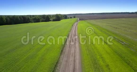 一条灰色的长路在犁地和绿田之间视频的预览图