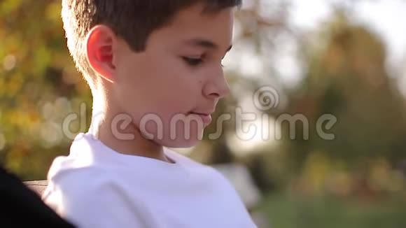 把穿白色毛衣的少年男孩关在长凳上带背包的帅哥学校男孩视频的预览图