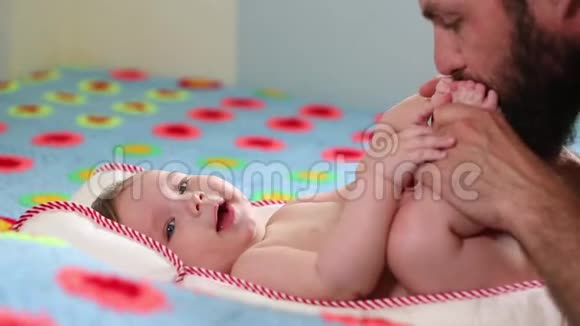 胡子父亲千禧一代和他新生的孩子躺在床上玩概念父子一个男人和一个新生儿视频的预览图