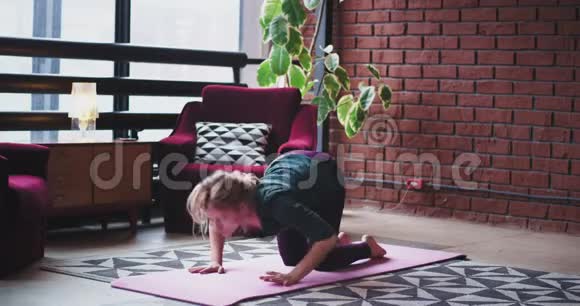 在城市生活设计中一位穿着粉色垫子的女士在家练习瑜伽她早上伸展身体以获得更多的锻炼视频的预览图