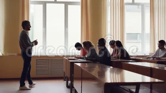 大胡子男大学的老师正在给成年学生读讲座做手势年轻人正在写作视频的预览图