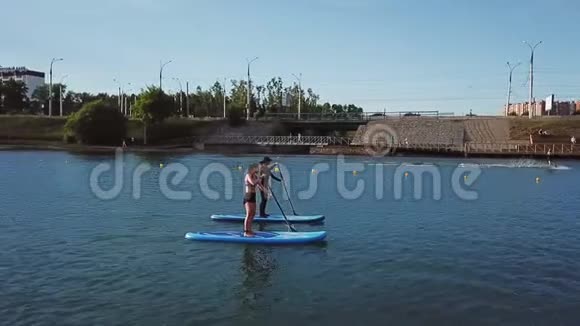 艾琳年轻夫妇和一个朋友在流血的湖面上的冲浪板上开会视频的预览图