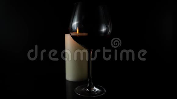一杯酒和一支黑色背景上燃烧的蜡烛视频的预览图
