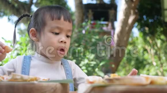 可爱的饥饿的女孩喜欢在后院吃自制的披萨有家人的小女孩在户外的午餐桌上选择性泡沫视频的预览图