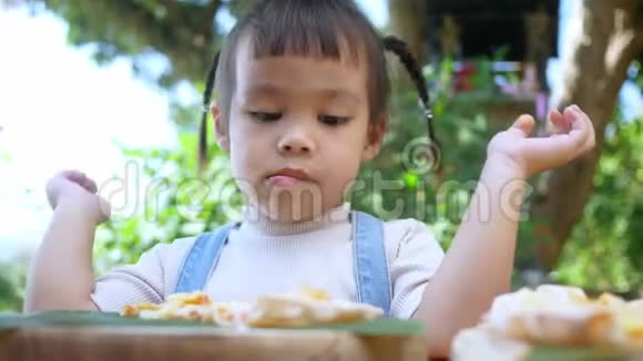 可爱的饥饿的女孩喜欢在后院吃自制的披萨有家人的小女孩在户外的午餐桌上选择性泡沫视频的预览图