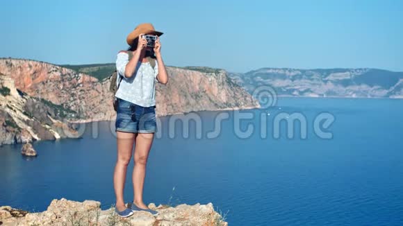微笑女性背包客享受暑假用相机拍照海景视频的预览图