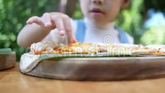 可爱的饥饿的女孩喜欢在后院吃自制的披萨有家人的小女孩在户外的午餐桌上选择性泡沫视频的预览图