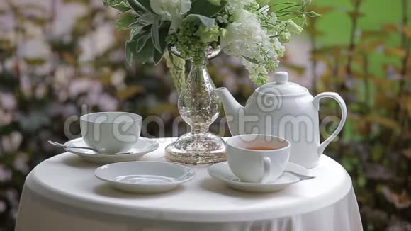 美丽的年轻黑发女人穿着浴袍喝着茶在露台上放松白杯热茶视频的预览图