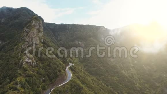 在西班牙特内里费的蛇形公路上的一辆汽车的鸟瞰图绿色金丝雀山脉的雨天早晨视频的预览图