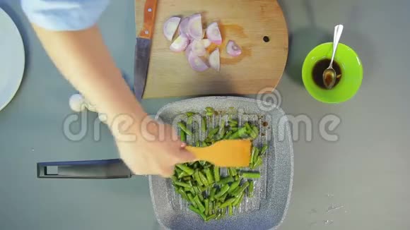 一个女人用木铲把新鲜的绿豆混合成一锅沸腾的油视频的预览图