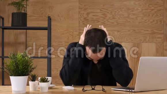 沮丧的商人抱着他的头坐在办公室里视频的预览图