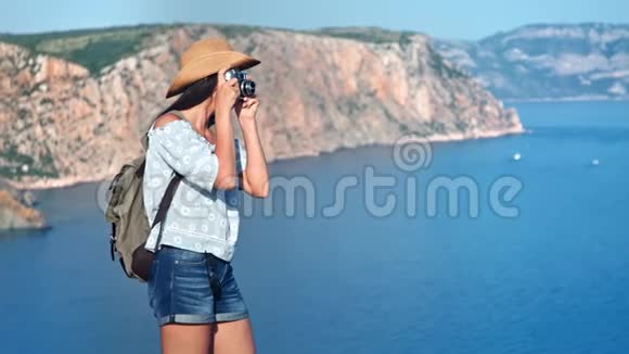 微笑背包客女游客用相机拍摄美丽的海景视频的预览图