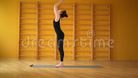 苏里亚纳马斯卡穿黑色紧身衣的女人在楼梯背景的黄色工作室做瑜伽练习健康生活方式视频的预览图