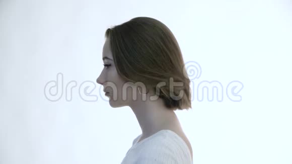 一个年轻漂亮的女人在白色背景上的形象梦幻般地抬起头来视频的预览图