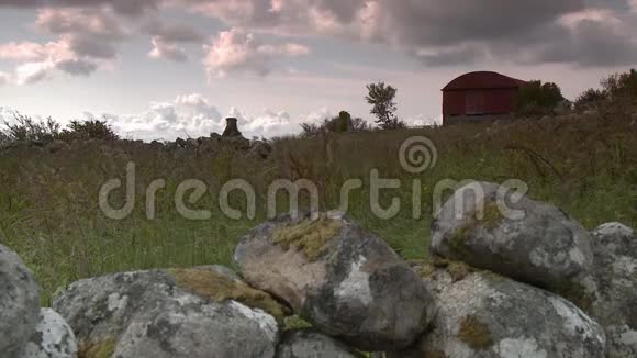 一座红色的谷仓在一片田野和山墙后面视频的预览图
