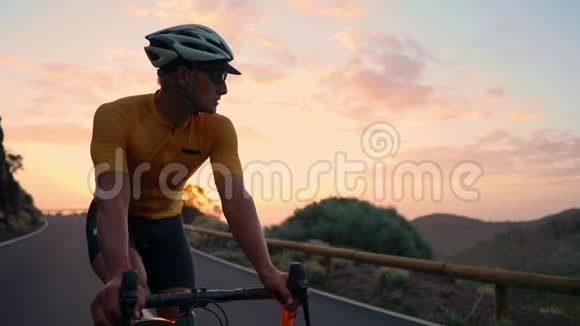 一个骑自行车的人骑着自行车在山路上的日落时看着相机慢动作稳定视频的预览图
