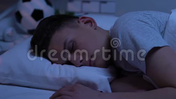 十几岁的孩子静静地睡在床上车灯经过辛苦了一天后休息视频的预览图