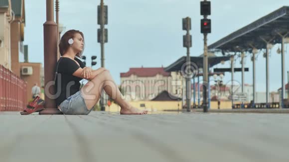 伤心的女孩坐在火车站的瓷砖上耳机里哭视频的预览图