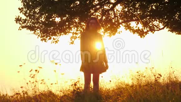 带太阳镜的女孩剪影在令人惊叹的日落中旋转视频的预览图