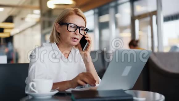 漂亮的商务小姐在咖啡馆里用手提电脑和手机聊天视频的预览图