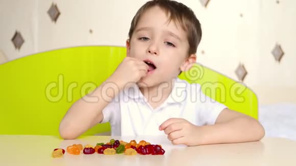 一个小孩子正坐在房间里的桌子旁吃着明亮的糖果孩子体验快乐的情绪视频的预览图