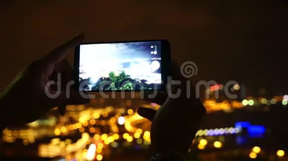 女性手与智能手机拍照或视频夜城视频的预览图