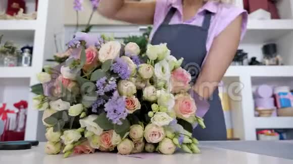 花商用纸特写的手包装玫瑰和叶子的花束视频的预览图