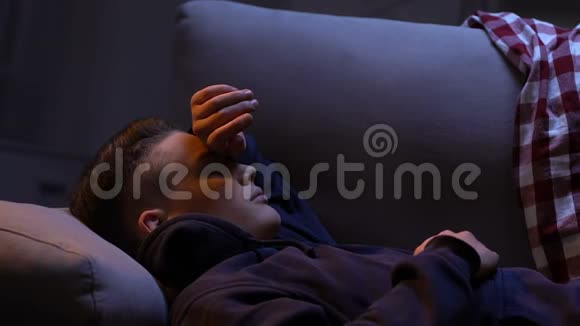 戴着头巾的少年躲在灯光下试图睡觉用手臂闭上眼睛视频的预览图