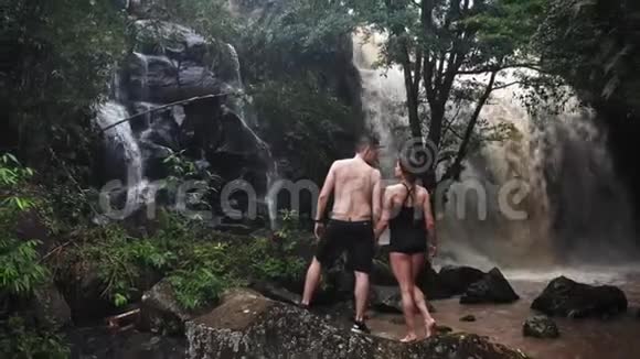 在洞穴瀑布下相爱的情侣一对情侣巴厘岛之旅做运动旅途空中射击旅行概念视频的预览图