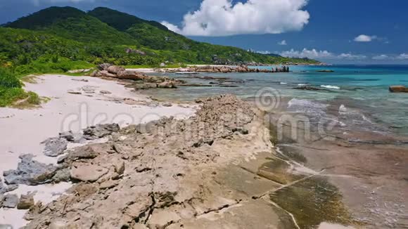 空中无人驾驶飞机在岩石般的热带海岸线上缓慢地飞行花岗岩巨石和海浪又在悬崖岸边翻滚视频的预览图