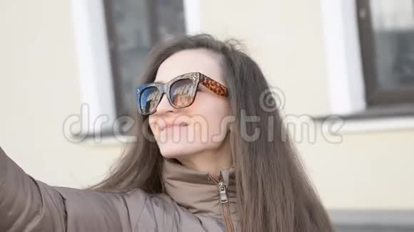 一个年轻漂亮的女学生穿着西装戴着眼镜穿过城市视频通话自拍抱着一个人的肖像视频的预览图