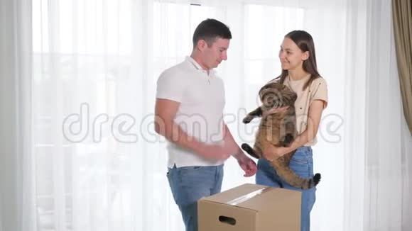 丈夫和妻子在新房子里带着盒子和可爱的猫视频的预览图