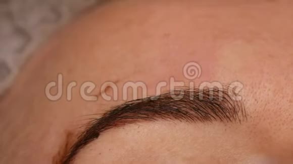 一位戴手套的美容师使用一种特殊的针头在眉毛的皮肤下涂上一种色素眉毛形状视频的预览图
