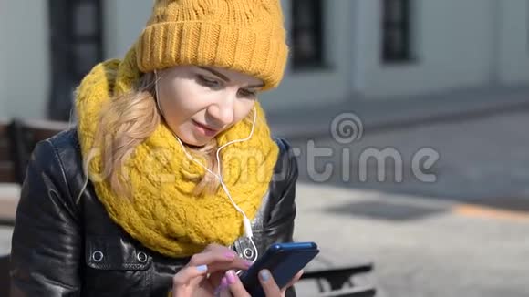 城市街头用智能手机耳机听音乐的少女画像视频的预览图