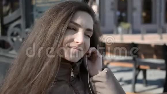 城市街道上年轻可爱迷人的年轻女孩的肖像背景是用耳机听音乐视频的预览图