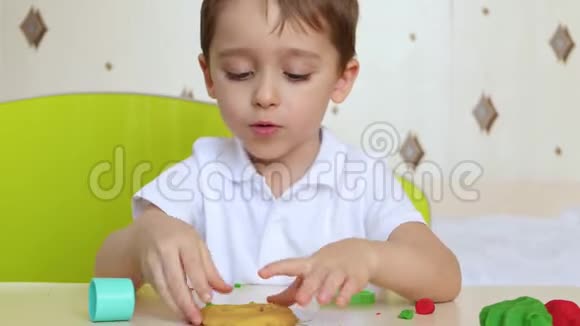 一个开朗爱笑的男孩为工作玩模特混合游戏坐在桌边的孩子雕刻着普拉蒂尼娜视频的预览图