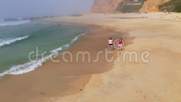 在海滩上度过美好的一天两个女孩穿过沙滩视频的预览图
