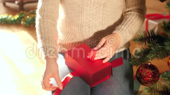 4k视频年轻女子用圣诞礼物在盒子上系红丝带蝴蝶结视频的预览图