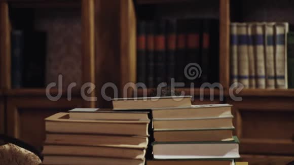 人书呆子在惊讶的脸之间成堆的书在图书馆书架在背景留胡子的教师或学生视频的预览图