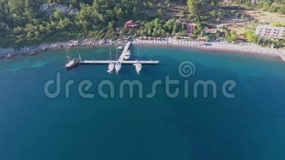 帆船停泊在靠近海滩的码头无人机的视野视频的预览图