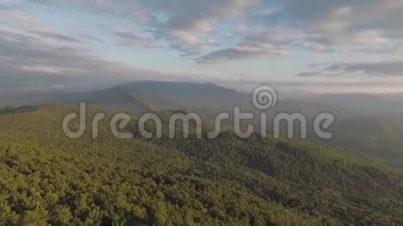 一架无人机飞过覆盖着森林的山顶傍晚自然景观视频的预览图