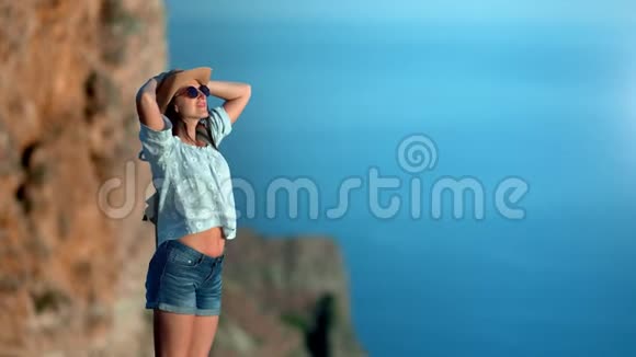 放松的旅行时髦女性站在山上欣赏大海视频的预览图