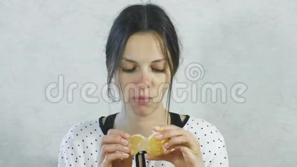 女孩脸上甜蜜情感布鲁内特女人吃着甜橘子微笑着视频的预览图