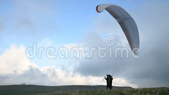 一名男性运动员滑翔伞在黄昏云的背景下在室外升起一只翅膀但不能飞行失败视频的预览图