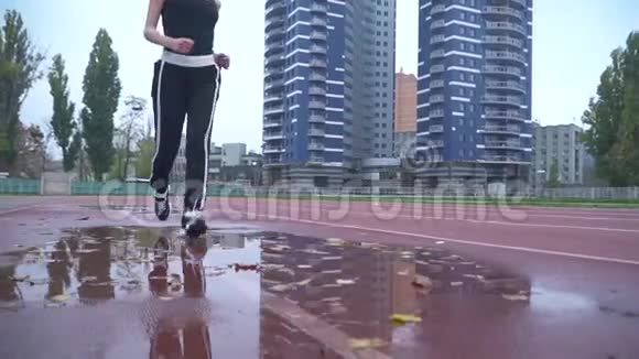 穿着运动鞋裤子和t恤的漂亮女孩在户外的水坑里奔跑视频的预览图