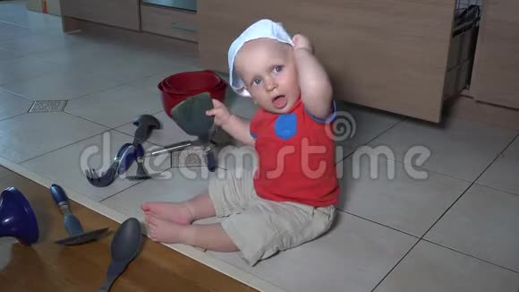 可爱的孩子带着厨师帽在厨房里搞得一团糟幼儿在地板上玩耍视频的预览图